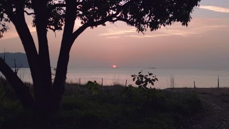 The-sun-is-setting-over-the-tranquil-ocean,-painting-the-sky-in-warm-colors