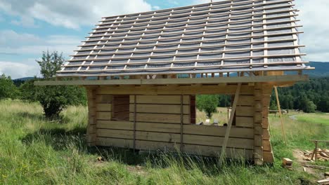 Casa-De-Madera-En-Construcción,-Hecha-De-Troncos-Y-Ubicada-En-Un-Hermoso-Paisaje-Bajo-Un-Cielo-Azul.