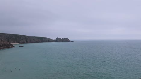 Luftaufnahme-über-Dem-Strand-Von-Porthcurno-Mit-Menschen,-Die-Im-Meer-Schwimmen