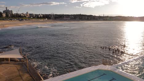 Erhöhte-Ansicht-Von-Menschen,-Die-Bei-Sonnenaufgang-Im-Meer-Neben-Bondi-Eisbergen-Schwimmen