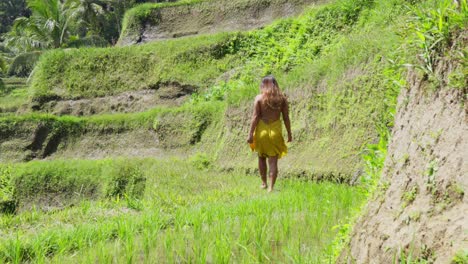 Hermosa-Mujer-Asiática-Camina-Sobre-Una-Terraza-De-Arroz-Y-Se-Da-La-Vuelta,-Cámara-Lenta,-Cámara-En-Mano