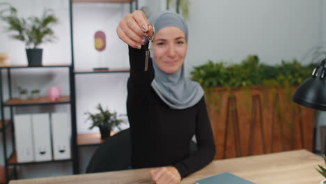 Muslim-woman-real-estate-agent-showing-keys-of-new-home-house-apartment,-buying-or-renting-property