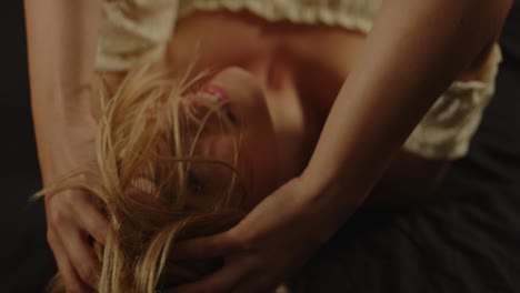 A-sexy-blond-woman-wildly-plays-with-her-beautiful-hair-while-lying-in-bed