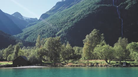 Wunderschöne-Seeszene-Mit-Türkisfarbenem-Wasser-Und-Felsigem-Ufer,-Umgeben-Von-Einer-Natürlichen-Landschaft