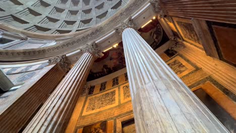 Low-angle-tilting-up-of-Corinthian-columns-and-artwork-inside-Pantheon,-Rome,-Italy