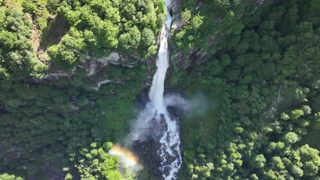 Aerial-view-of-a-majestic-waterfall-cascading-through-the-lush-Maggiatal-Vallemaggia-forest-in-Ticino,-Switzerland