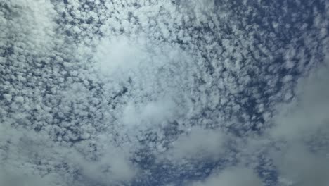 Glorious-ever-changing-sky-dotted-with-high-cirrus-clouds-and-an-airplane-crossing-the-scene-from-right-to-left-climbing