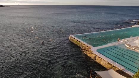 Vista-Elevada-De-Personas-Nadando-En-El-Océano-Y-La-Piscina-En-Bondi-Icebergs-Al-Amanecer