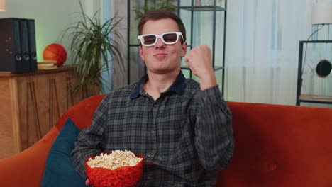 Mann-Sitzt-Auf-Der-Couch,-Isst-Popcorn-Und-Schaut-Sich-Zu-Hause-Interessante-Fernsehserien-Und-Sportspiele-Online-An