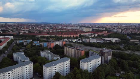 Modernes-Europäisches-Stadtbild-Mit-Wohngebäuden,-Einer-Autobahn-Und-üppigen-Grünflächen-Unter-Einem-Bewölkten-Himmel-Bei-Sonnenuntergang