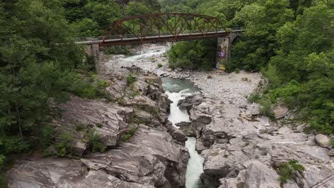 Vista-Aérea-De-Un-Puente-Sobre-Un-Río-Montañoso-En-El-Valle-De-Maggiatal,-Tesino,-Suiza