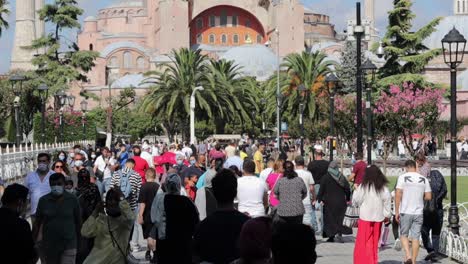 People-walk-through-a-pedestrian-area-in-Istanbul,-Turkey,-with-the-Hagia-Sophia-Grand-Mosque-in-the-backdrop