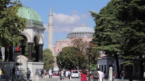 People-stroll-through-a-pedestrian-area-in-Istanbul,-Turkey,-with-the-Hagia-Sophia-Grand-Mosque-in-the-background