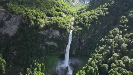 Aerial-view-of-a-waterfall-cascading-down-the-cliffs-in-Maggiatal-Vallemaggia,-Tessin,-Switzerland