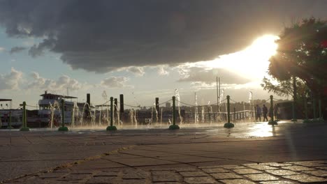 Weite-Aufnahme-Eines-Springbrunnens-Auf-Einem-Pier-Mit-Blick-Auf-Den-Hudson-River-Bei-Sonnenuntergang