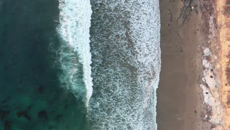 Imágenes-Aéreas-De-Olas-Que-Se-Deslizan-Suavemente-Sobre-Una-Playa-Tranquila-En-California