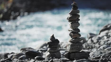 Detailed-footage-of-rock-stacks-on-a-riverbank,-with-flowing-water-creating-a-serene-atmosphere