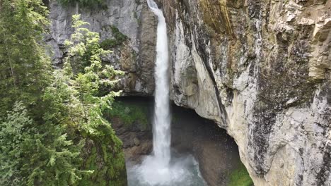 Bergli-Stüber-Waterfall-cascading-into-a-pool-surrounded-by-rocky-cliffs-and-lush-greenery-in-Fätschbach,-Glarus-Süd,-Switzerland