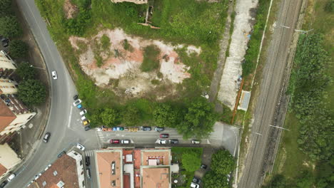 A-residential-area-near-railway-tracks-with-trees-and-parked-cars,-aerial-view