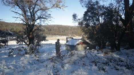 A-bushman-collects-fire-wood-and-carries-back-to-a-traditional-hut-in-the-snow-in-the-Victorian-high-country