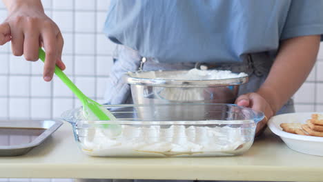 Mujer-Preparando-Pastel-De-Tiramisú,-Esparciendo-La-Crema-Sobre-La-Capa-De-Galletas-En-Un-Recipiente-De-Vidrio