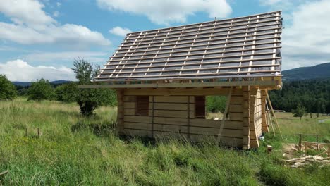 Wooden-house-under-construction,-made-of-logs-and-located-in-beautiful-landscape---mountain-area