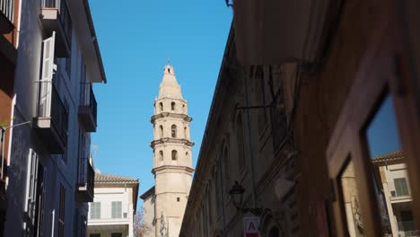 Charming-street-scene-capturing-classic-Spanish-architecture-and-a-tower-in-Palma,-Mallorca