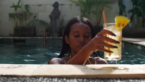 Asian-model-in-bikini-swims-to-poolside-with-refreshing-tropical-cocktail