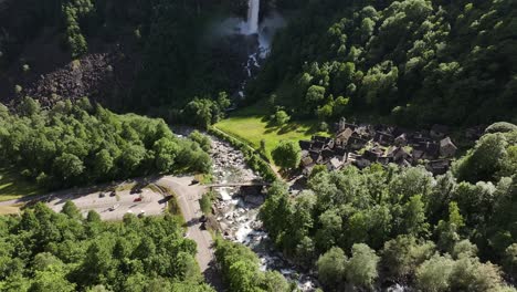 Aerial-view-of-a-small-village-situated-just-below-a-waterfall-in-Maggiatal-Vallemaggia,-Tessin,-Switzerland