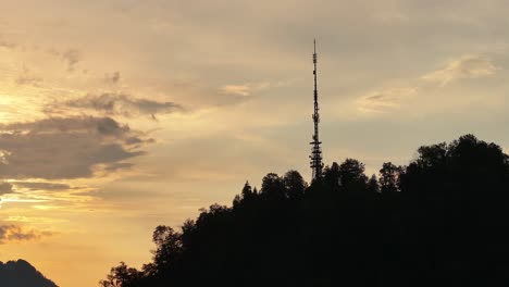 Luftaufnahme-Eines-Hügels-Mit-Einem-Fernsehturm-Bei-Sonnenuntergang-In-Glarus-Nord,-Schweiz