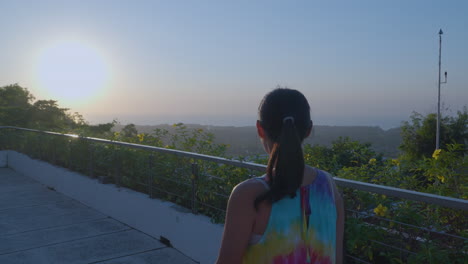 Back-View-Of-Female-Traveler-At-Terrace-Of-Luxury-Hotel-With-Ocean-Views-At-Sunset-In-Uluwatu,-Bali,-Indonesia