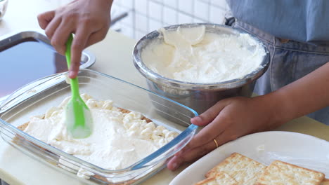 Mujer-Haciendo-Pastel-De-Tiramisú,-Aplicando-Crema-Sobre-La-Capa-De-Galletas-Según-Receta