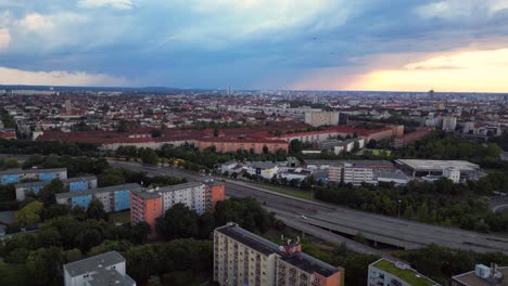 Modernes-Europäisches-Stadtbild-Mit-Wohngebäuden,-Einer-Autobahn-Und-üppigen-Grünflächen-Unter-Einem-Bewölkten-Himmel-Bei-Sonnenuntergang