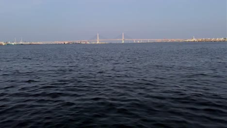 Calm-waters-of-a-bay-with-a-distant-view-of-a-bridge-under-a-clear-blue-sky