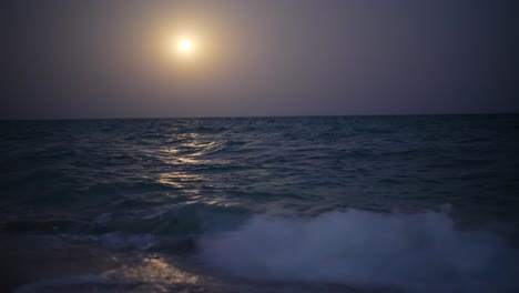 hazy-blue-tinted-weather-man-wades-into-the-shimmering-ocean-waves-sparkle-softly-under-starlight,-casting-a-magical-glow-over-the-Persian-Gulf-tranquil,-tropical-coastline-in-iran-nature-landscape