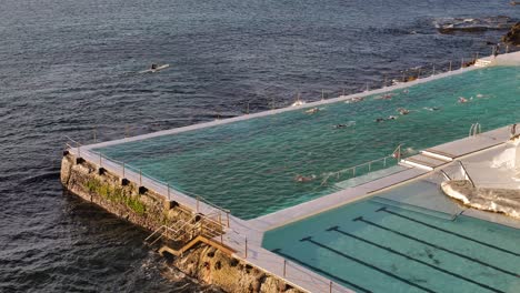 Erhöhte-Ansicht-Von-Menschen,-Die-Bei-Sonnenaufgang-Im-Pool-Bei-Bondi-Icebergs-Schwimmen