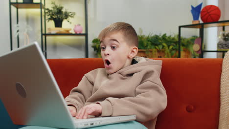 Amazed-teen-boy-use-laptop-computer,-receive-good-news-message,-shocked-by-victory,-celebrate-win