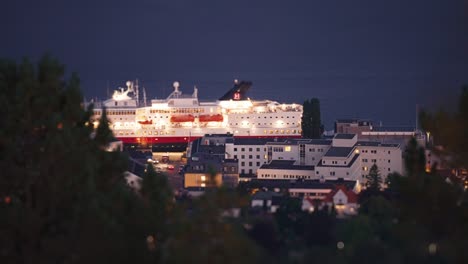 Das-Faszinierende-Bild-Des-Hafens-Von-Molde-Bei-Nacht,-Als-Das-Hell-Erleuchtete-Hurtigruten-Kreuzfahrtschiff-Anmutig-Den-Hafen-Verlässt