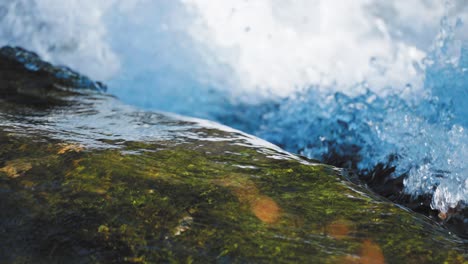 Slow-motion-shot-of-the-transparent-clean-water-flowing-over-the-rocky-bottom