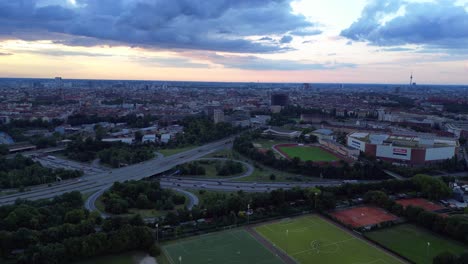 Fußballfelder-Umgeben-Von-Einer-Städtischen-Stadtlandschaft-Mit-Untergehender-Sonne,-Die-Einen-Warmen-Schein-Verbreitet