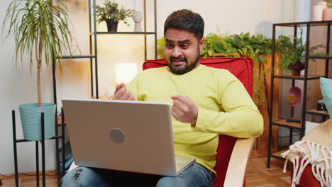 Amazed-Indian-man-use-laptop-computer,-receive-good-news-message-shocked-by-victory,-celebrate-win