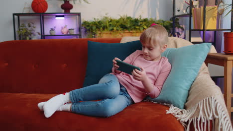 Worried-teen-child-girl-kid-enthusiastically-playing-racing-video-online-games-on-smartphone-at-home