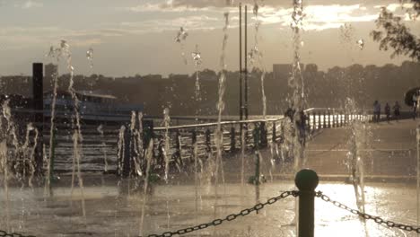 Zeitlupen-Schwenk-über-Einen-Springbrunnen-Auf-Einem-Pier-Mit-Blick-Auf-Den-Hudson-River-Bei-Sonnenuntergang