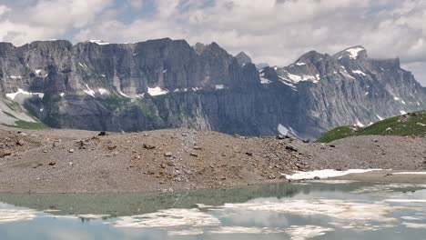 Glacial-lake-with-floating-ice-and-rocky-mountains-in-Klausenpass,-Urner-Boden,-Switzerland