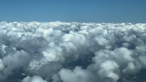 Immersive-pilot-POV-flying-over-some-tiny-cottony-and-fluffy-cumulus-clouds-in-a-sunny-day-and-blue-sky,-as-seen-by-the-pilots