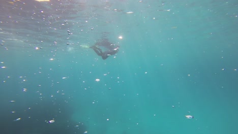 An-underwater-shot-of-a-snorkeler-from-below,-with-the-camera-moving-upwards-towards-the-surface