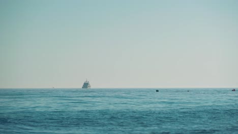 Mediterranean-Sea-with-dusky-sky,-luxury-yacht-on-the-distance-and-a-group-of-divers-closer-by