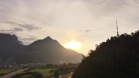 Sunset-over-the-mountains-with-a-communication-tower-and-village-in-Glarus-Nord,-Switzerland