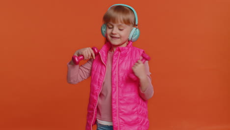 Cheerful-attractive-girl-listening-music-via-headphones-and-dancing-disco-fooling-around-having-fun