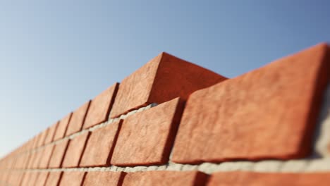 Brick-wall-made-out-of-clay-bricks-being-build-in-the-endless-animation-loop.-Filled-with-the-light-grey-cement.-Horizontal-camera-movement-at-the-completely-cloudless-blue-sky.-Loopable.